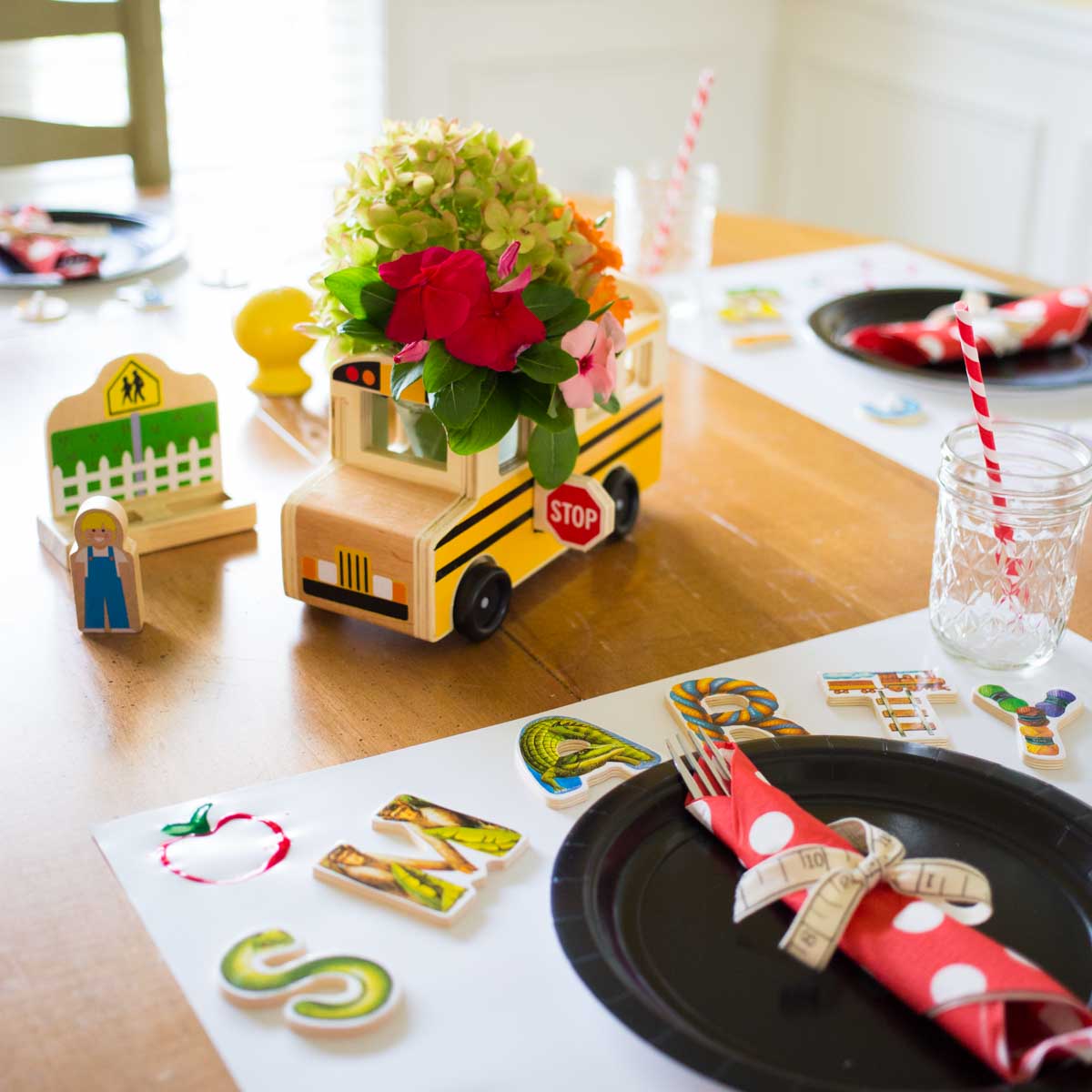 A table is set with a school bus floral centerpiece and cute ABC puzzle messages at each place setting.