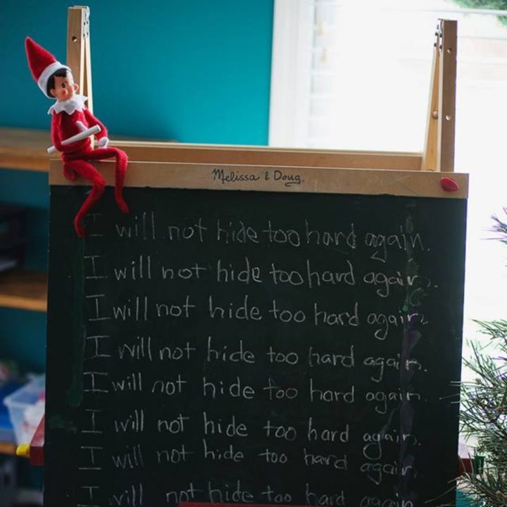 Elf on the Shelf sits on top of a Melissa & Doug chalkboard with a message that reads: "I will not hide too hard again."