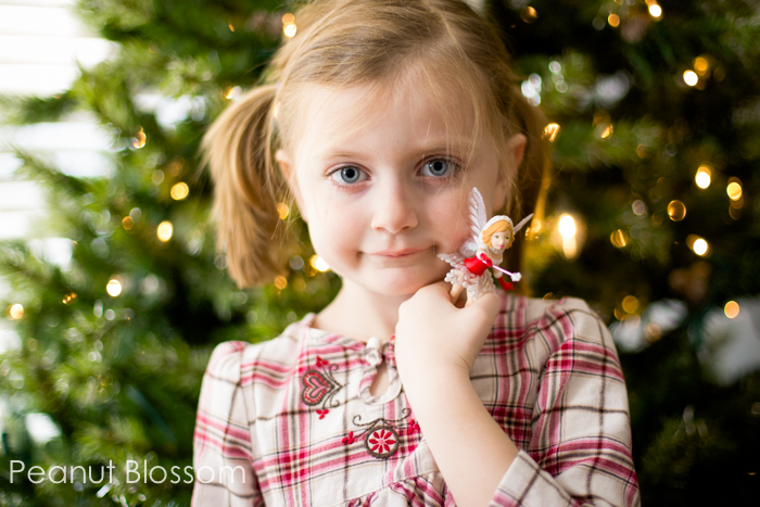A girl stands in front of a Christmas tree.