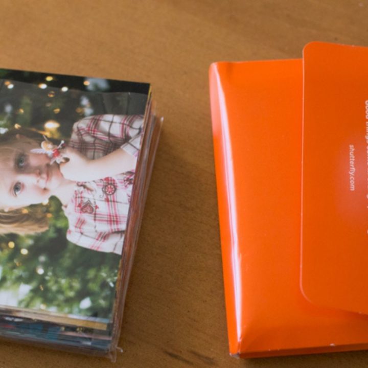 printed photos on a table next to the orange folder they arrived in.