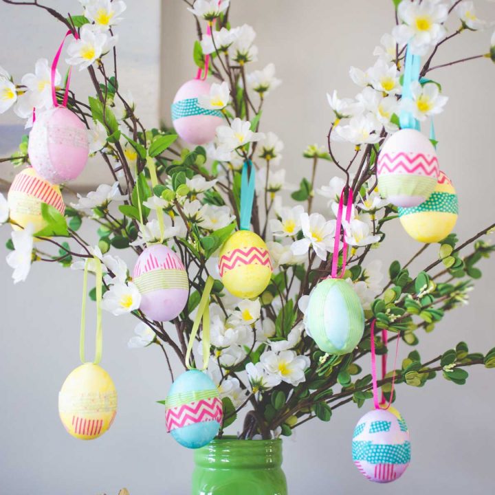 A homemade Easter Egg tree features pastel eggs wrapped in washi tape hanging from green branches.