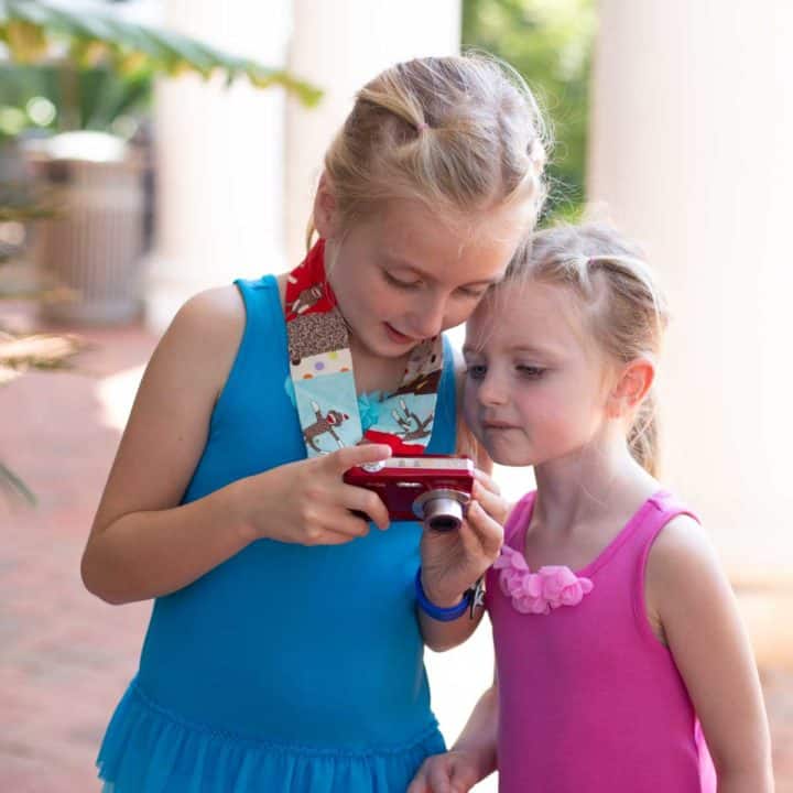 Two girls look at the photo on the back of a digital camera.