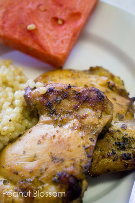 The cuban mojo chicken is on a plate with couscous and watermelon.