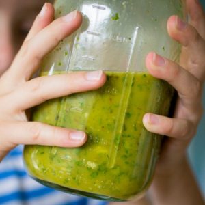 A girl holds a mason jar and is shaking up a batch of Cuban mojo marinade.