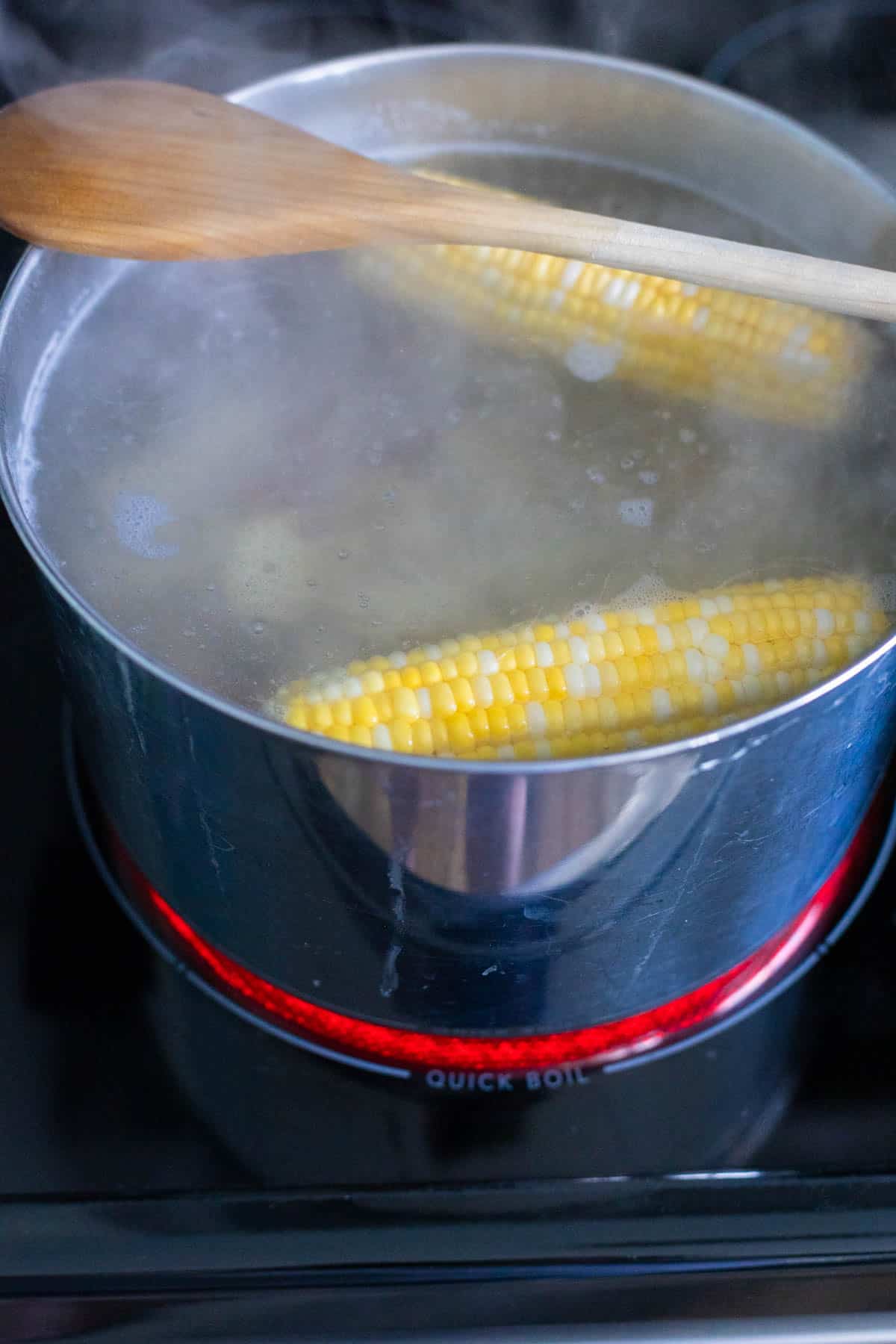 The corn cobs have been added to the boiling water in the large pot.
