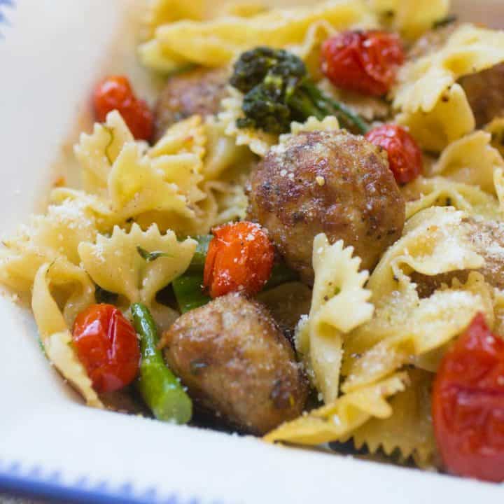 Bow tie pasta is tossed with roasted broccolini, roasted tomatoes, and chicken meatballs.