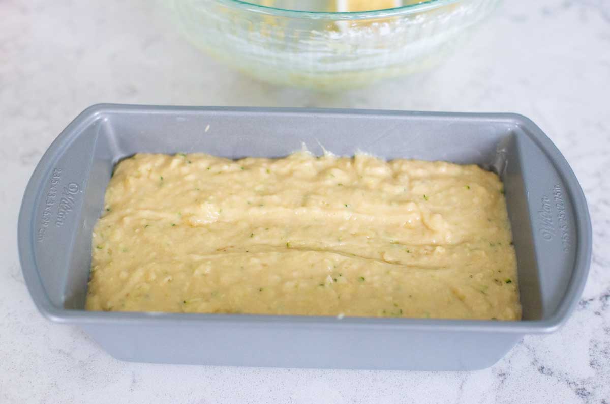 The batter for the banana zucchini bread has been spread into a metal baking pan.