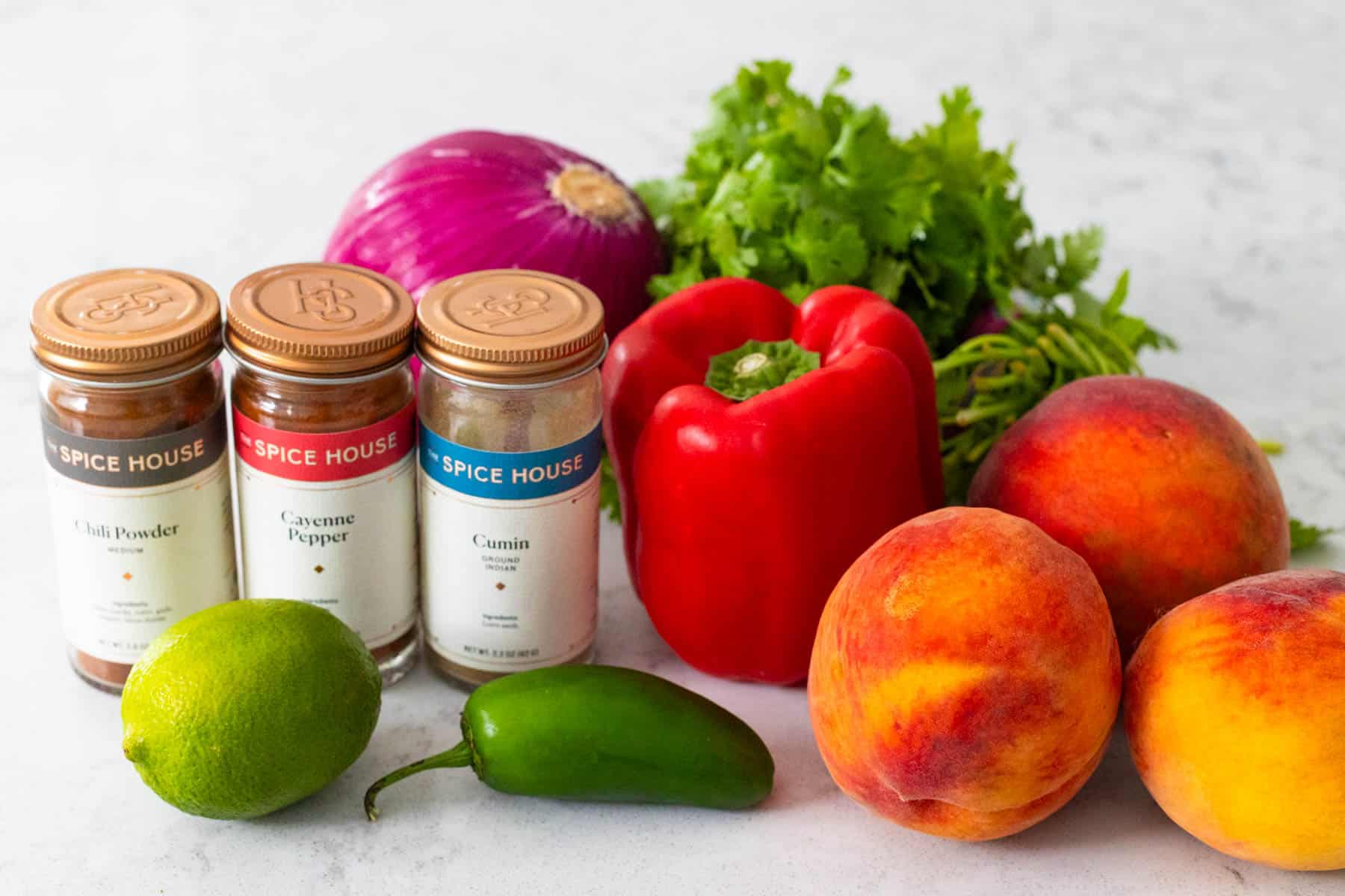 The fresh peaches, jalapeno pepper, and seasonings to make the peach salsa are on the counter.