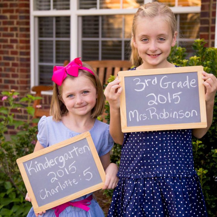 Two young girls hold chalkboards for their back to school photos.