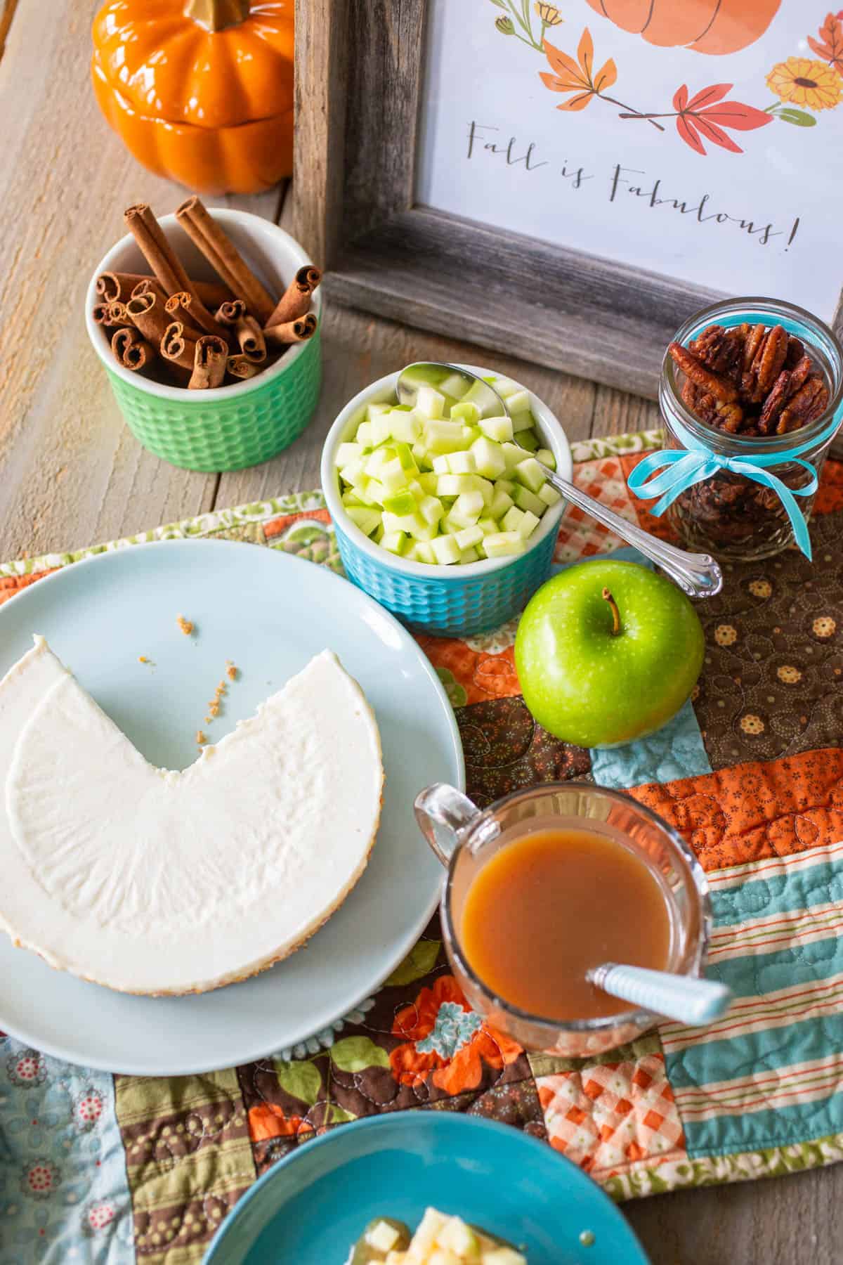 The plain cheesecake is surrounded by small dishes of the prepped toppings.