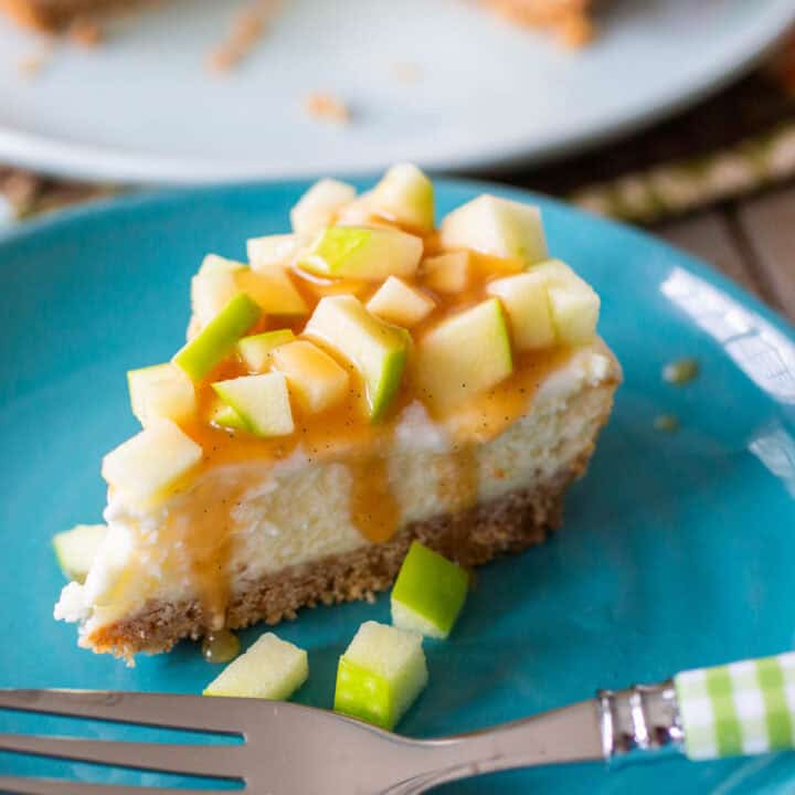 A slice of cheesecake topped with chopped apples and caramel sauce.