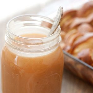 A mason jar filled with homemade caramel sauce with a spoon.