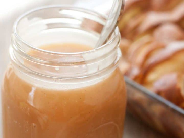 A mason jar filled with homemade caramel sauce with a spoon.