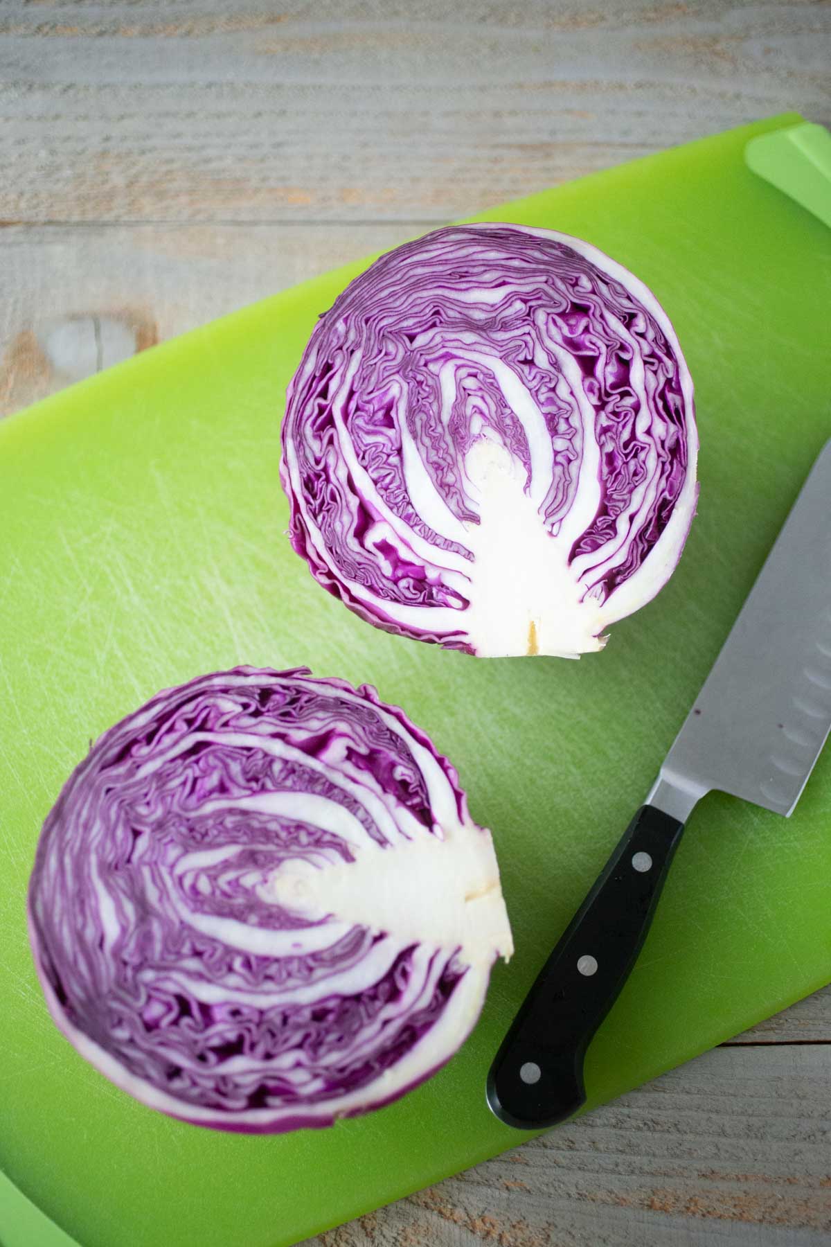 A head of purple cabbage has been sliced in half to show the core.