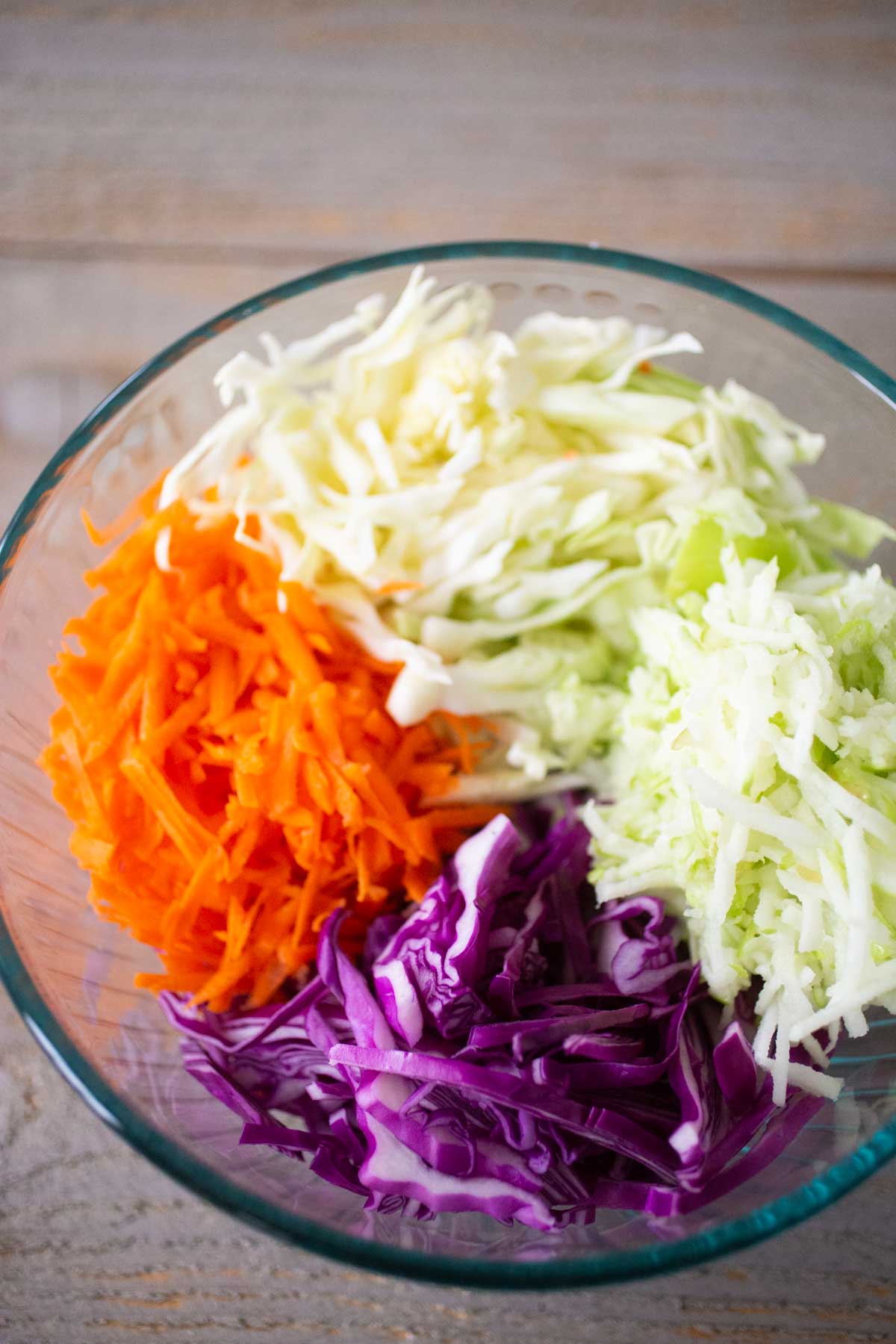 Shredded purple cabbage, shredded carrots, and shredded apples are ready to be made into slaw.