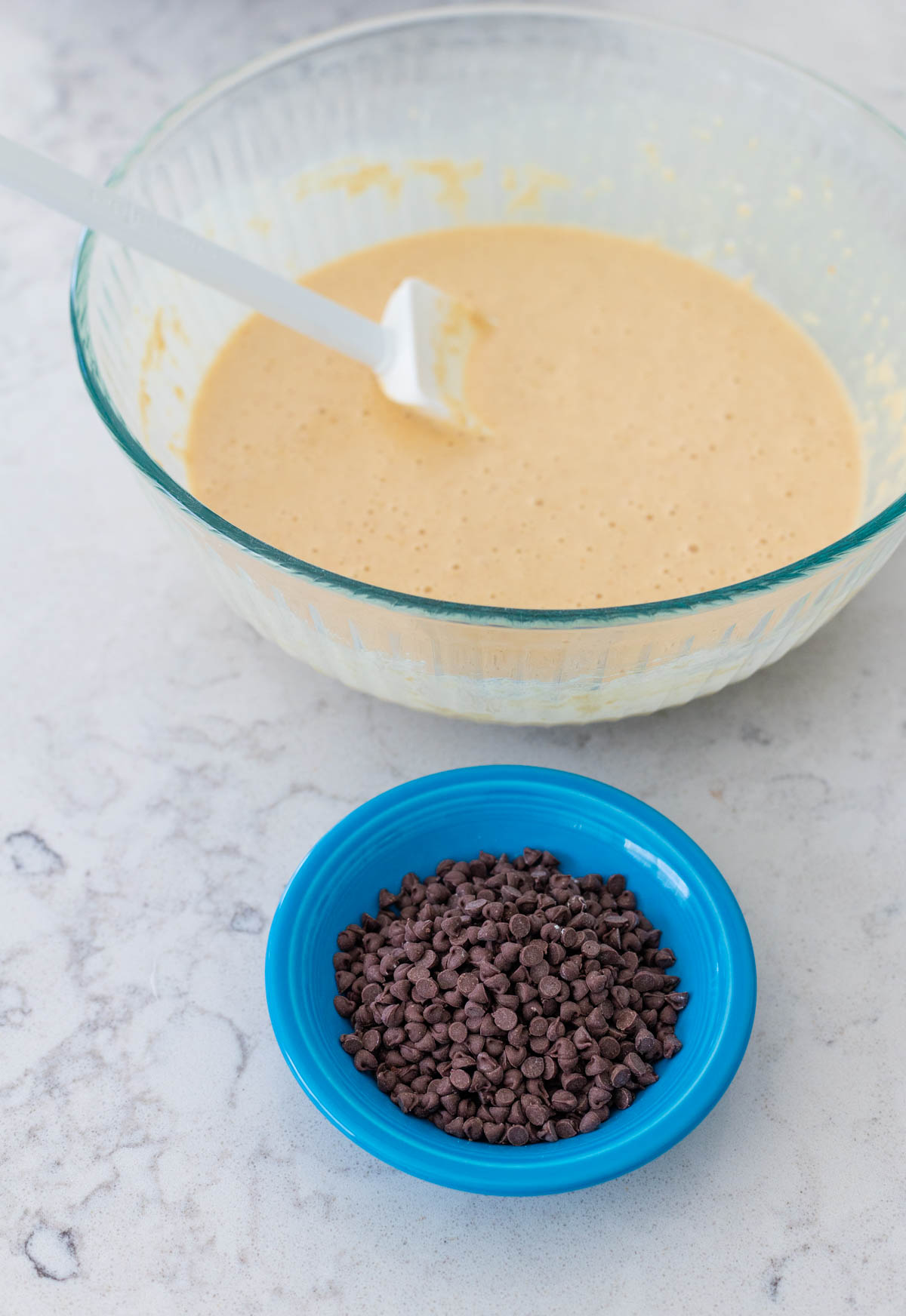 The mixed waffle batter has a bowl of mini chocolate chips ready to be added to it.