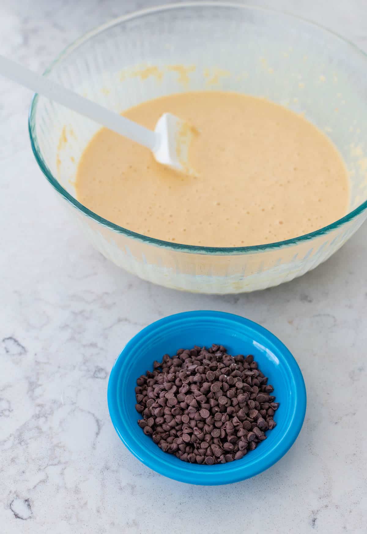 The mixed waffle batter has a bowl of mini chocolate chips ready to be added to it.