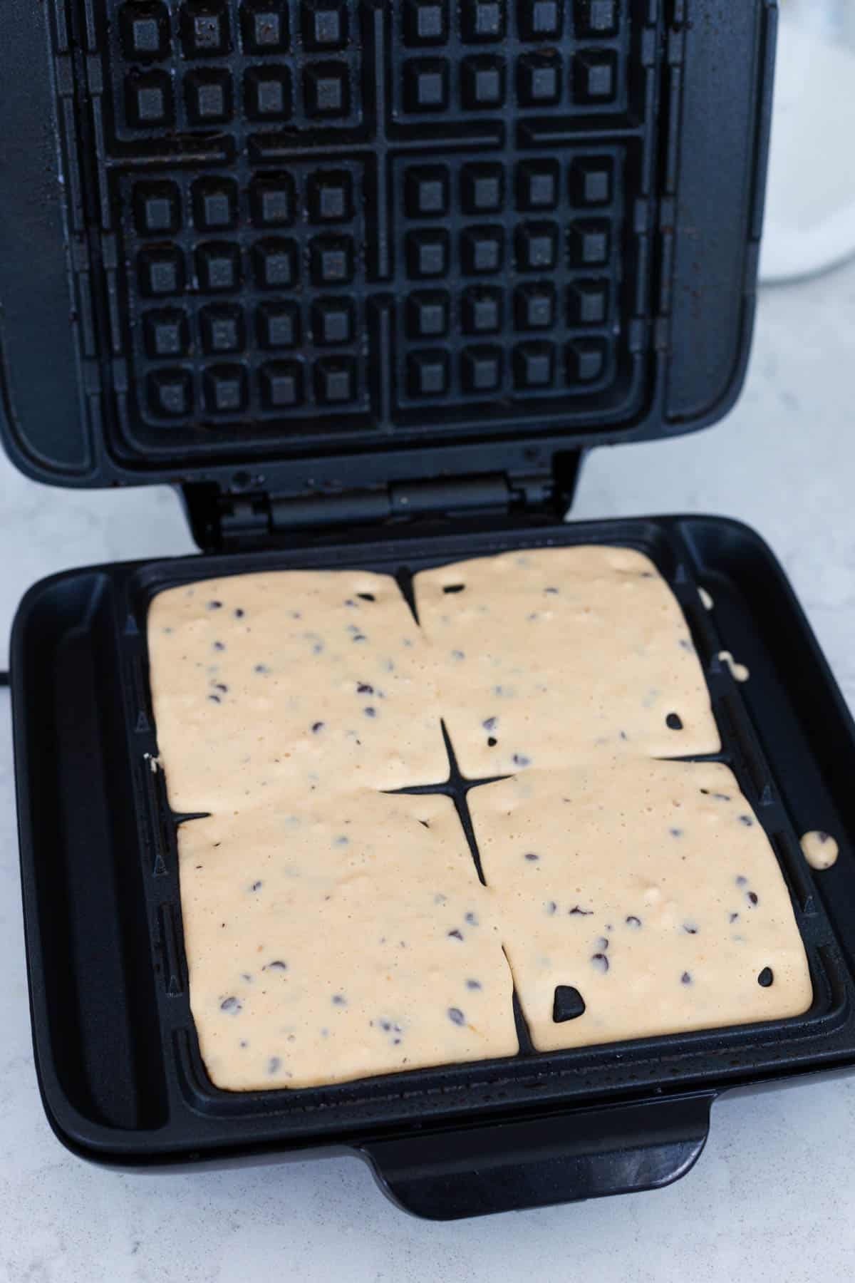 The peanut butter waffle batter has been poured into the hot waffle iron.