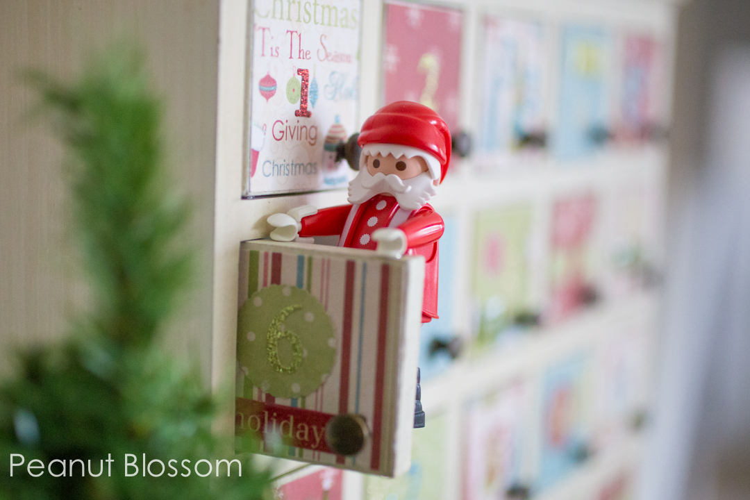 A Santa figurine pokes out of an advent calendar door.
