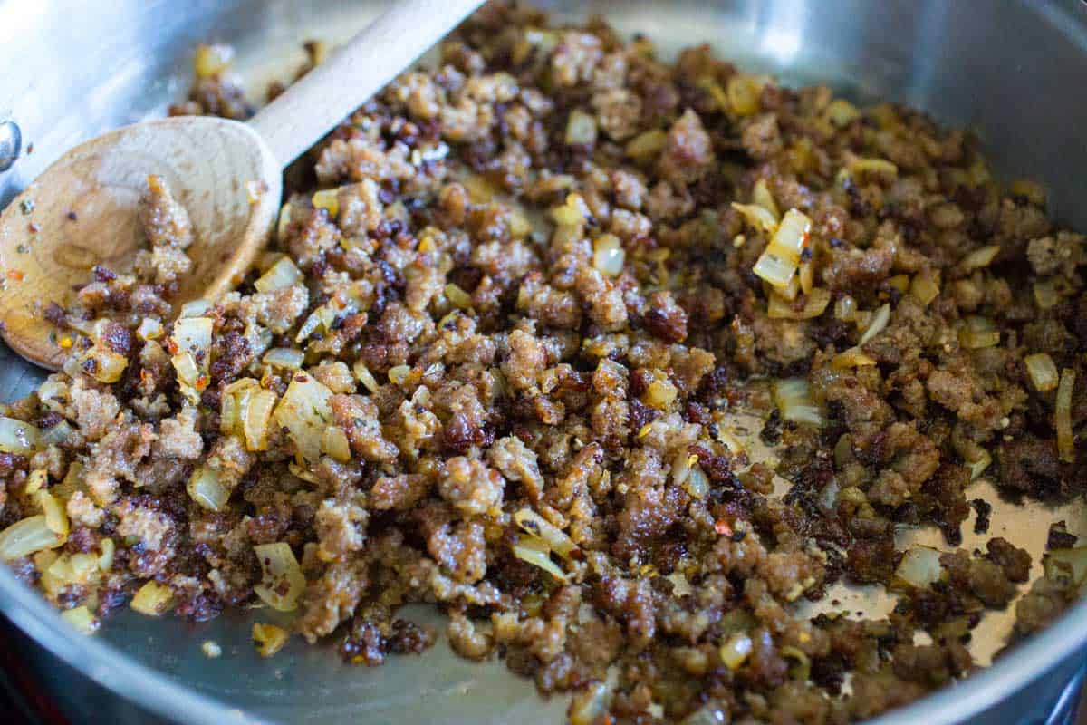 The browned sausage has been cooked until lightly toasted and the onions are soft.