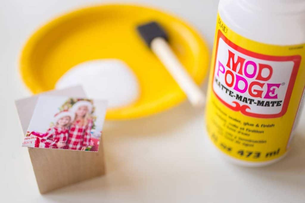 A plate with Mod Podge and a sponge brush ready to secure the photos to the wooden block