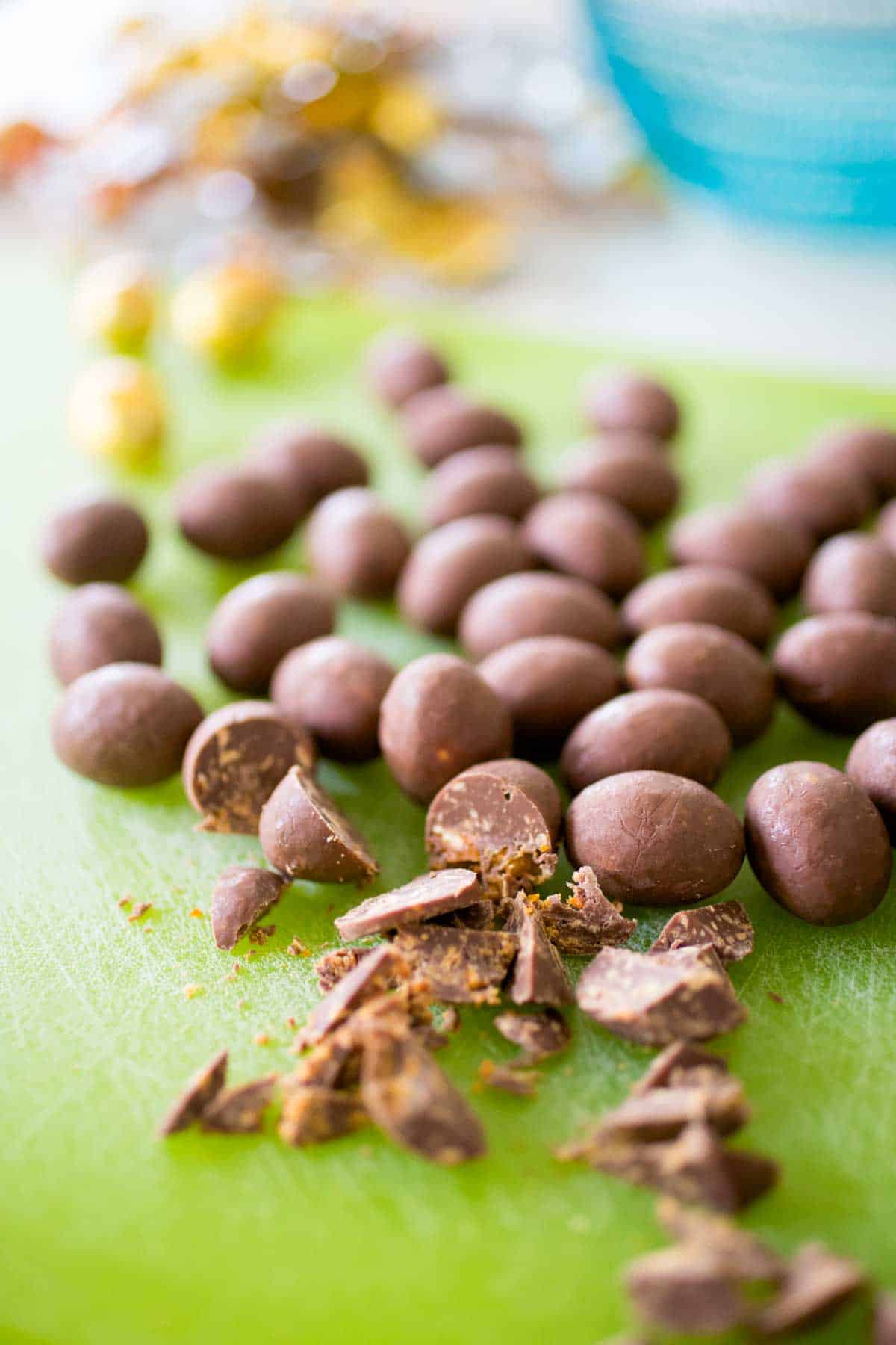 Chopped chocolates on a green cutting board.