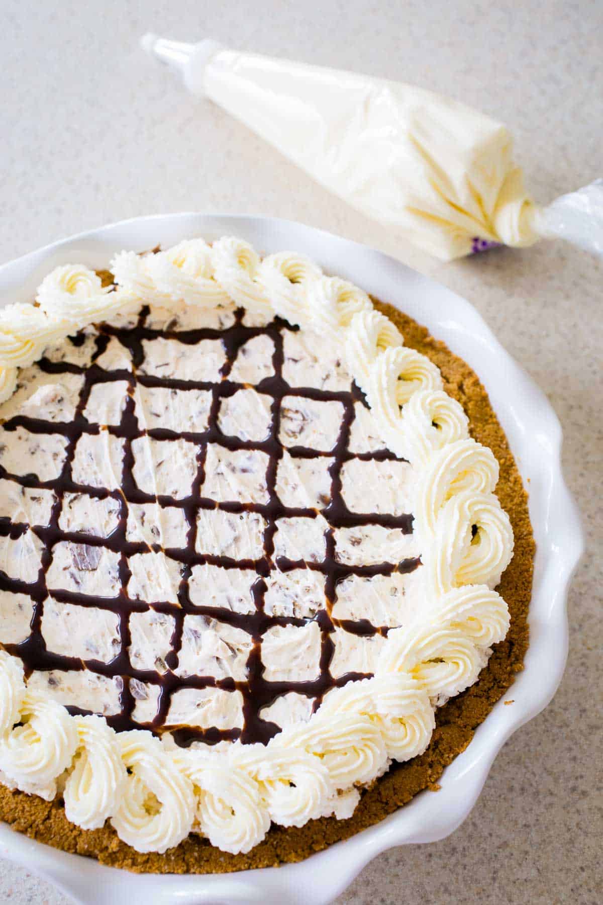 The finished pie has a chocolate drizzle lattice decoration with a piped whipped cream boarder.