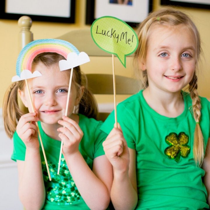 Two young girls in green shamrock shirts hold up St. Patrick's Day signs.