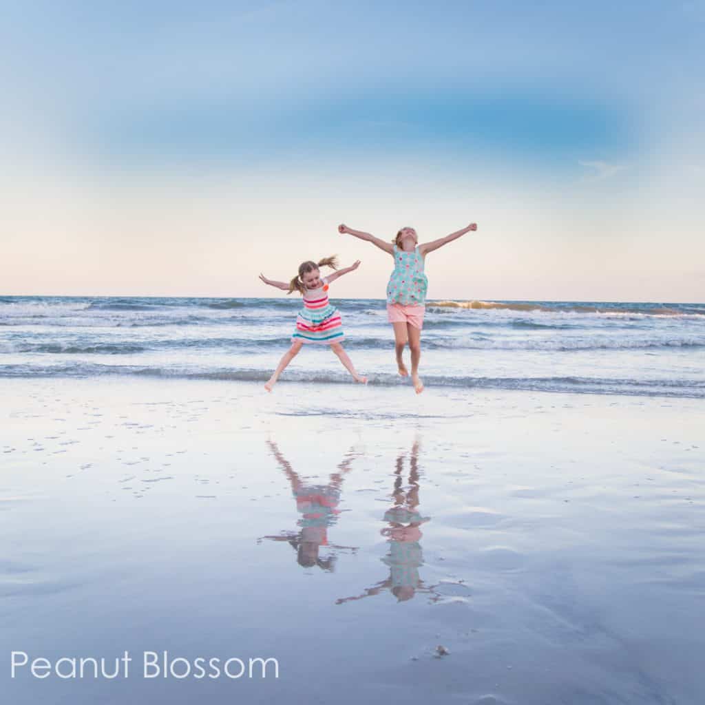 Girls jumping by the water in a beach family photo