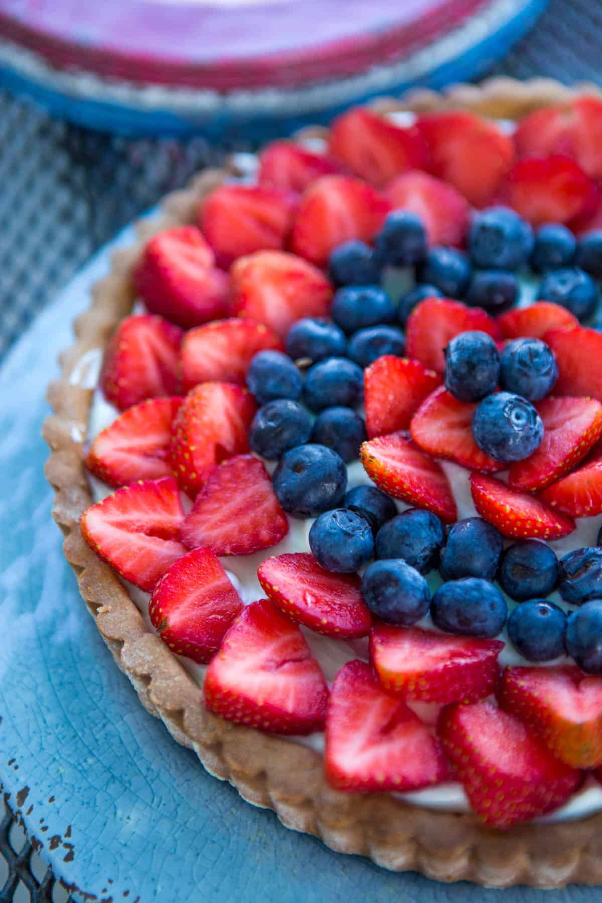 The finished tart has rows of fresh strawberries and blueberries arranged on top.