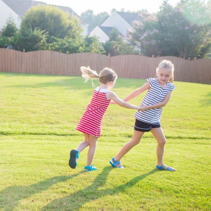 Two girls play a game in the backyard.