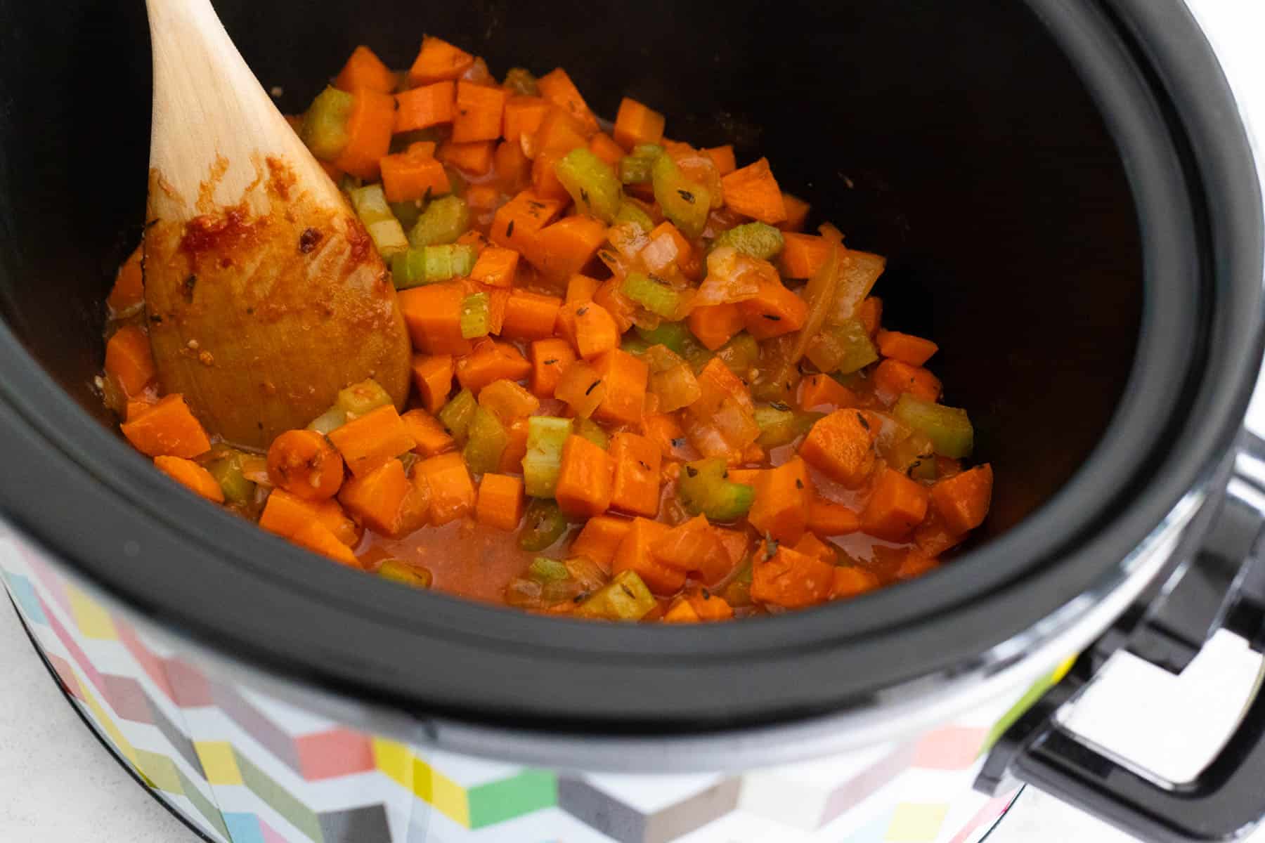 The vegetable mixture has been scraped into the slowcooker bowl.
