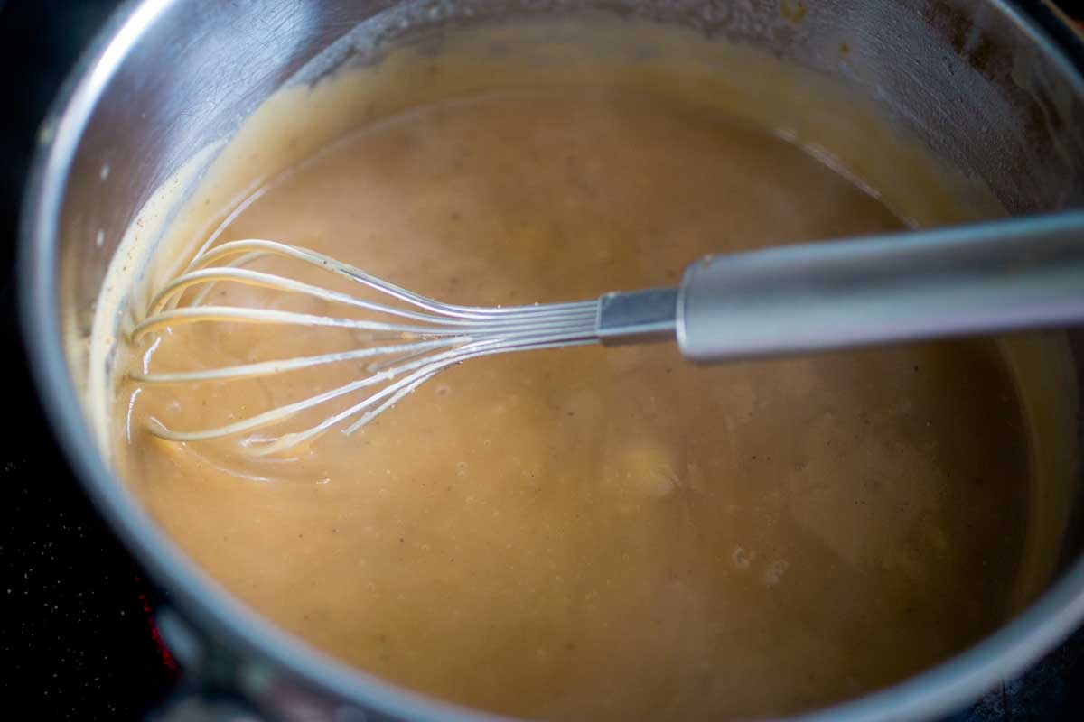 The beef broth has been added to the roux and it is creamy and thick.