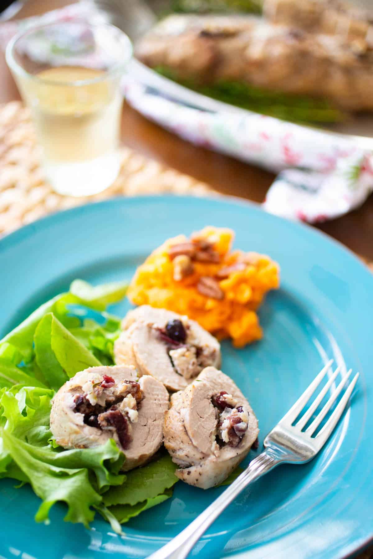 The dinner plate has 3 slices of pork next to a scoop of mashed sweet potatoes.