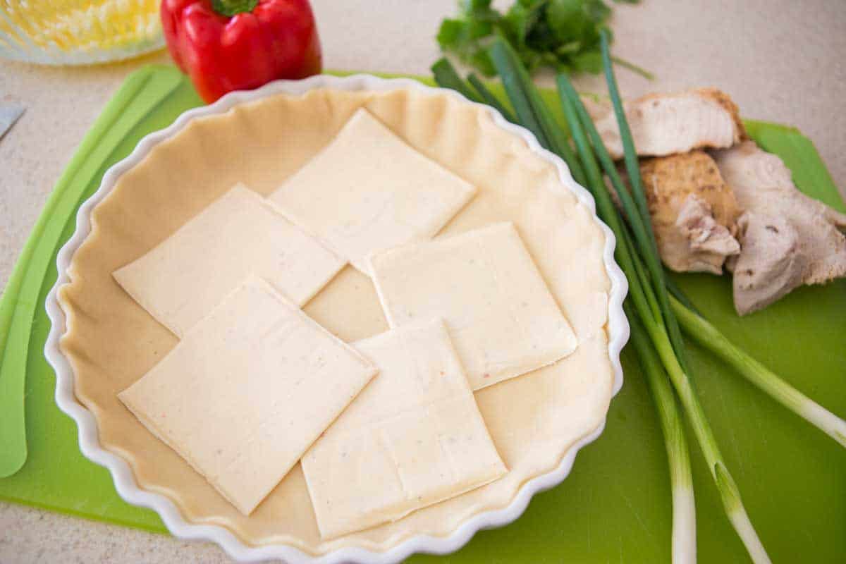 Cheese slices are laid over the bottom of the pie crust.