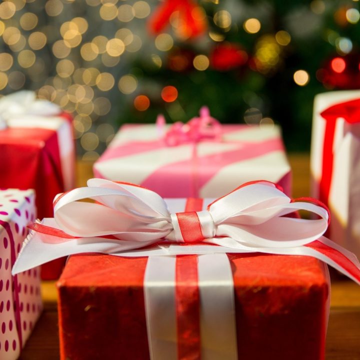 Several Christmas presents are wrapped in red paper with big white satin bows.
