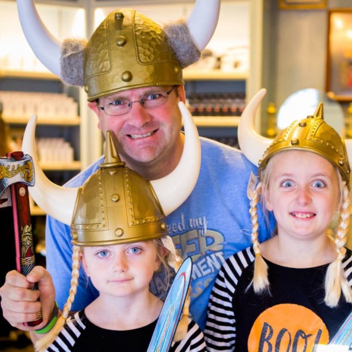 A dad and his daughters wearing VIkings helmuts.