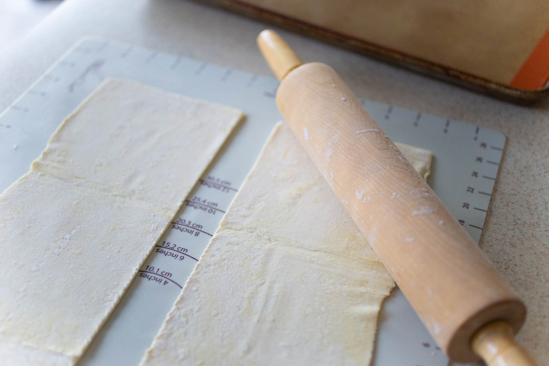 The dough has been rolled by a rolling pin on a baking mat.