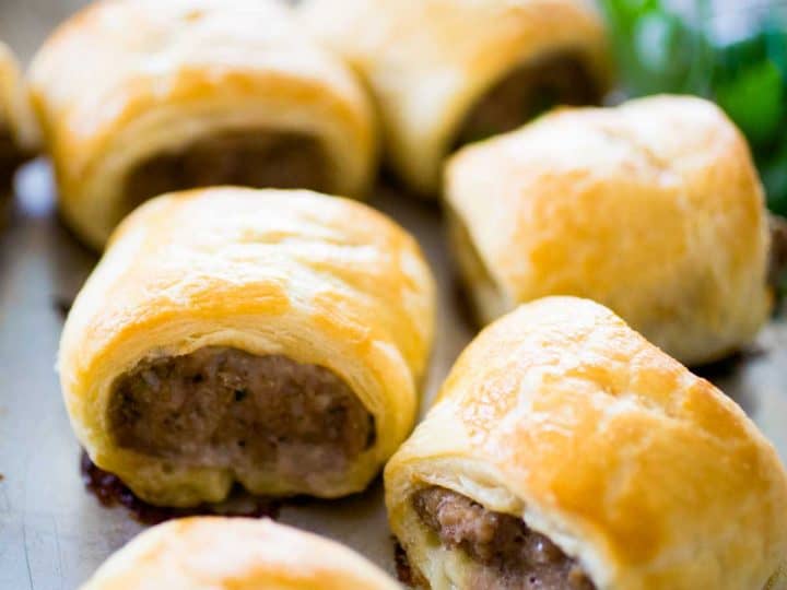 A tray of sausage rolls shows the golden brown puff pastry wrap and savory sausage filling.