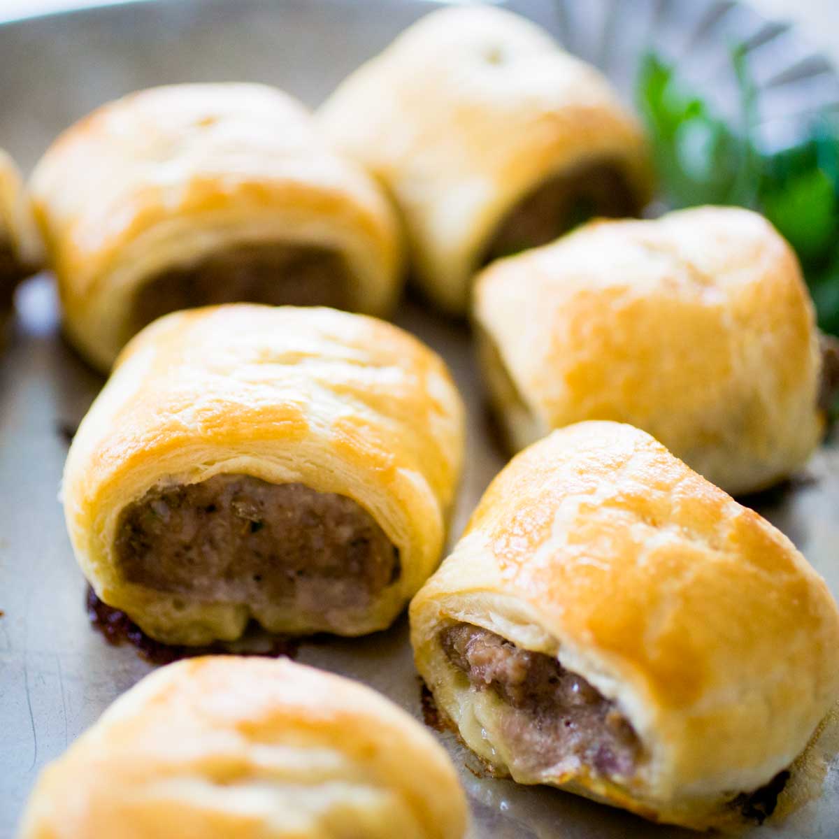 A tray of sausage rolls shows the golden brown puff pastry wrap and savory sausage filling.
