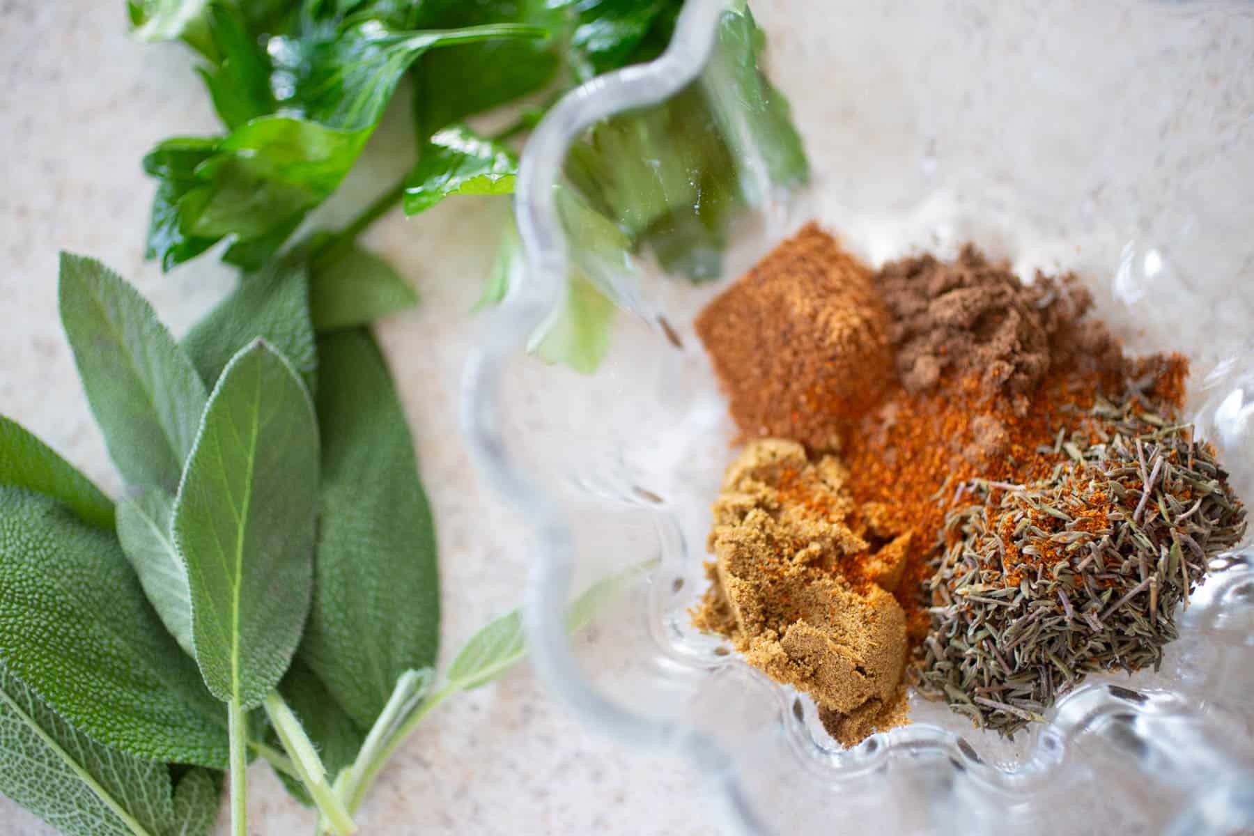 Fresh sage and a bowl filled with dried spices to season the pork sausage.