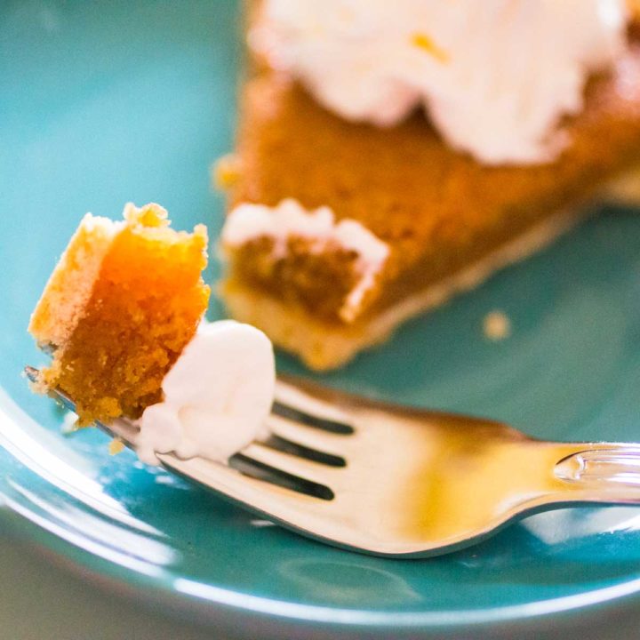A bite of treacle tart with whipped cream on a fork.