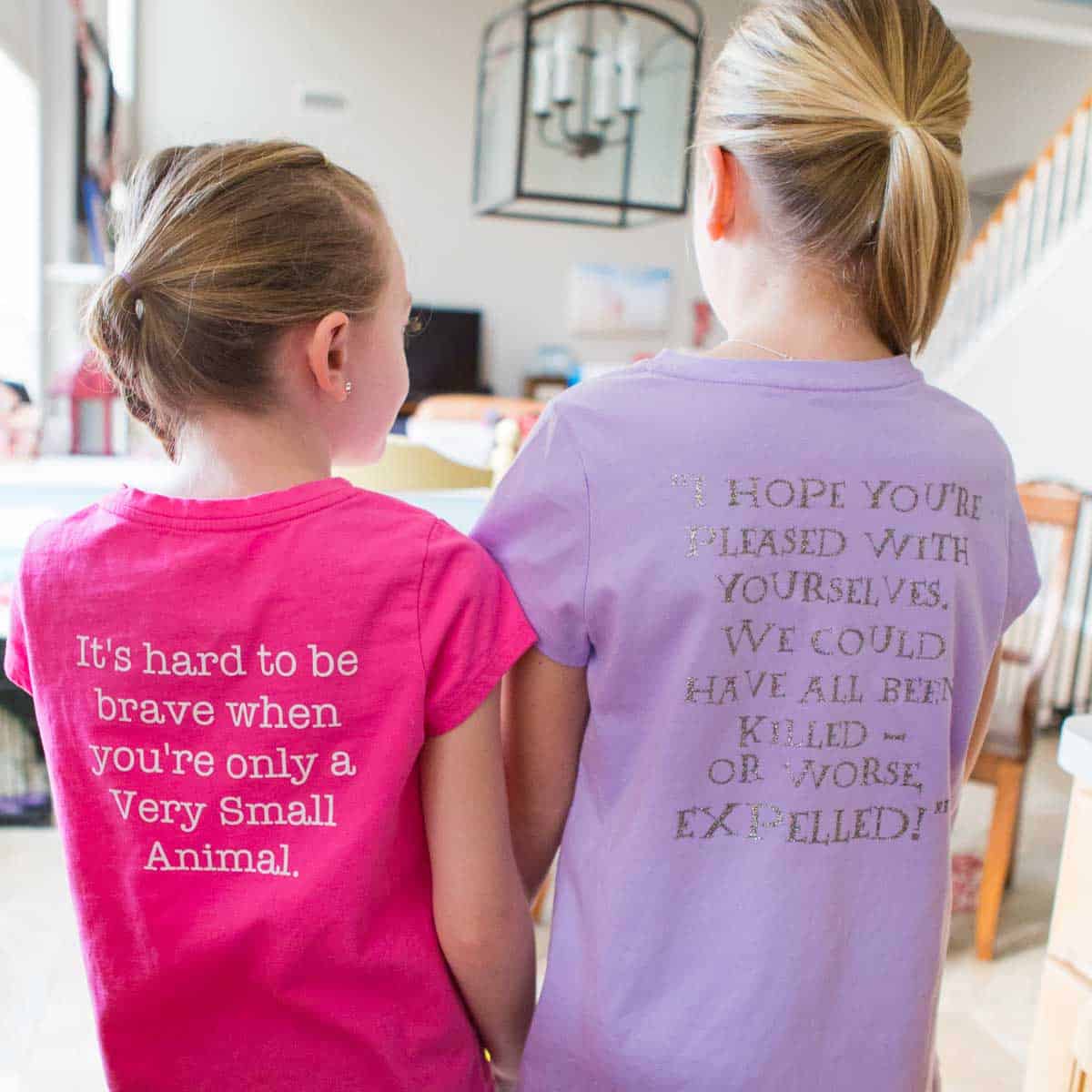 Two girls show the backs of their DIY book quotes t-shirts.