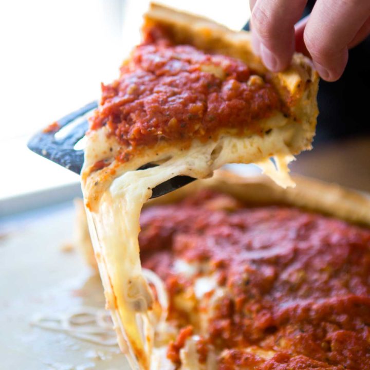A slice of Giordano's Chicago Deep Dish Pizza is being served with a long cheese pull of mozzarella.