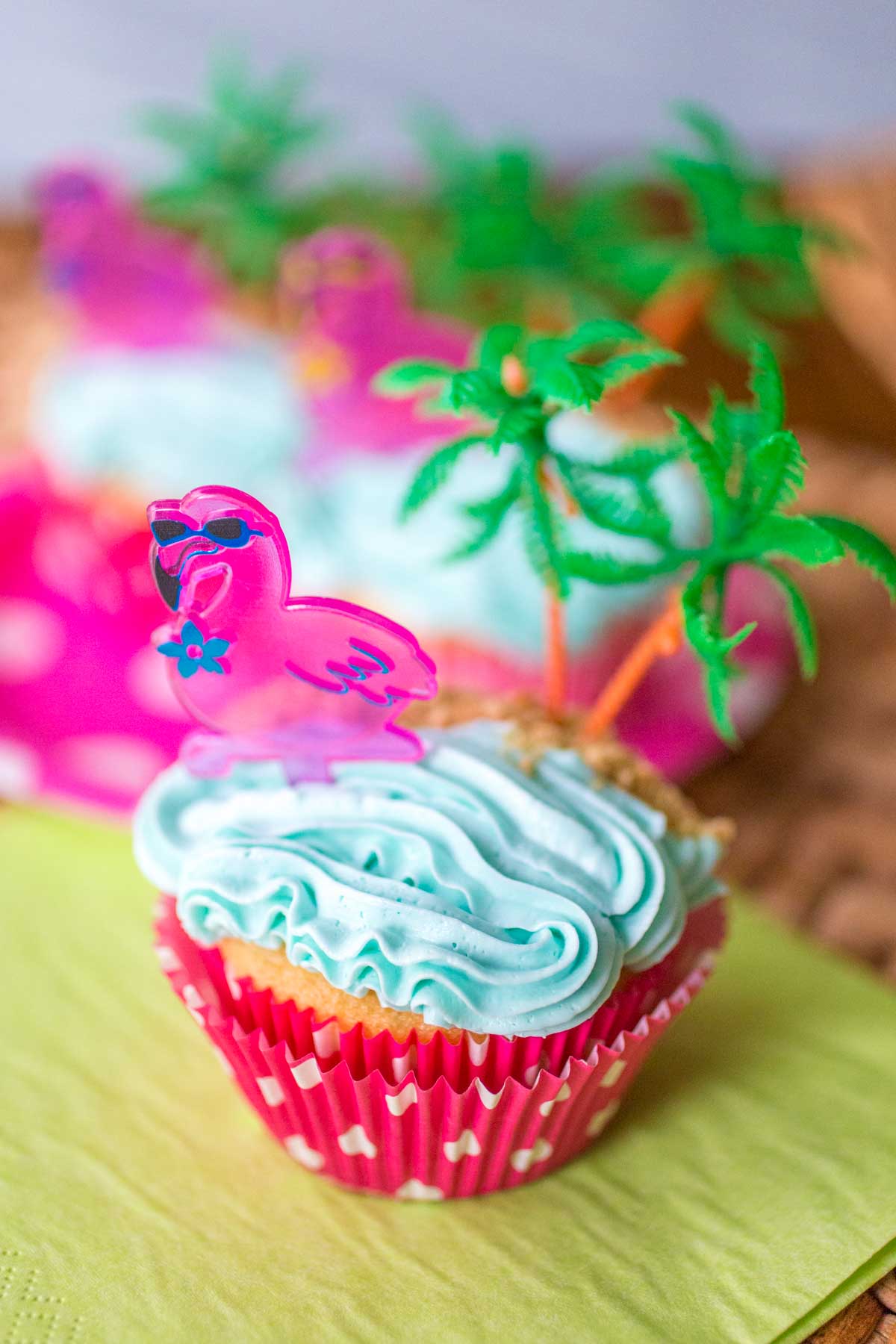 A pink flamingo cupcake with a plastic palm tree topper.