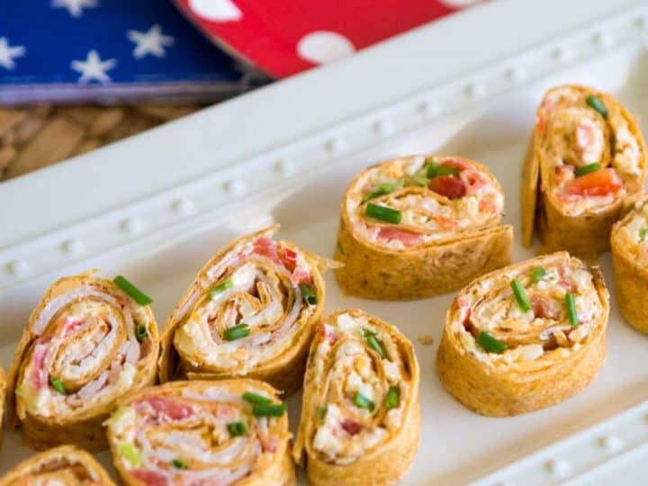 A platter of spicy firecracker pinwheels appetizers shows the meat and veggies rolled up in the tortilla.