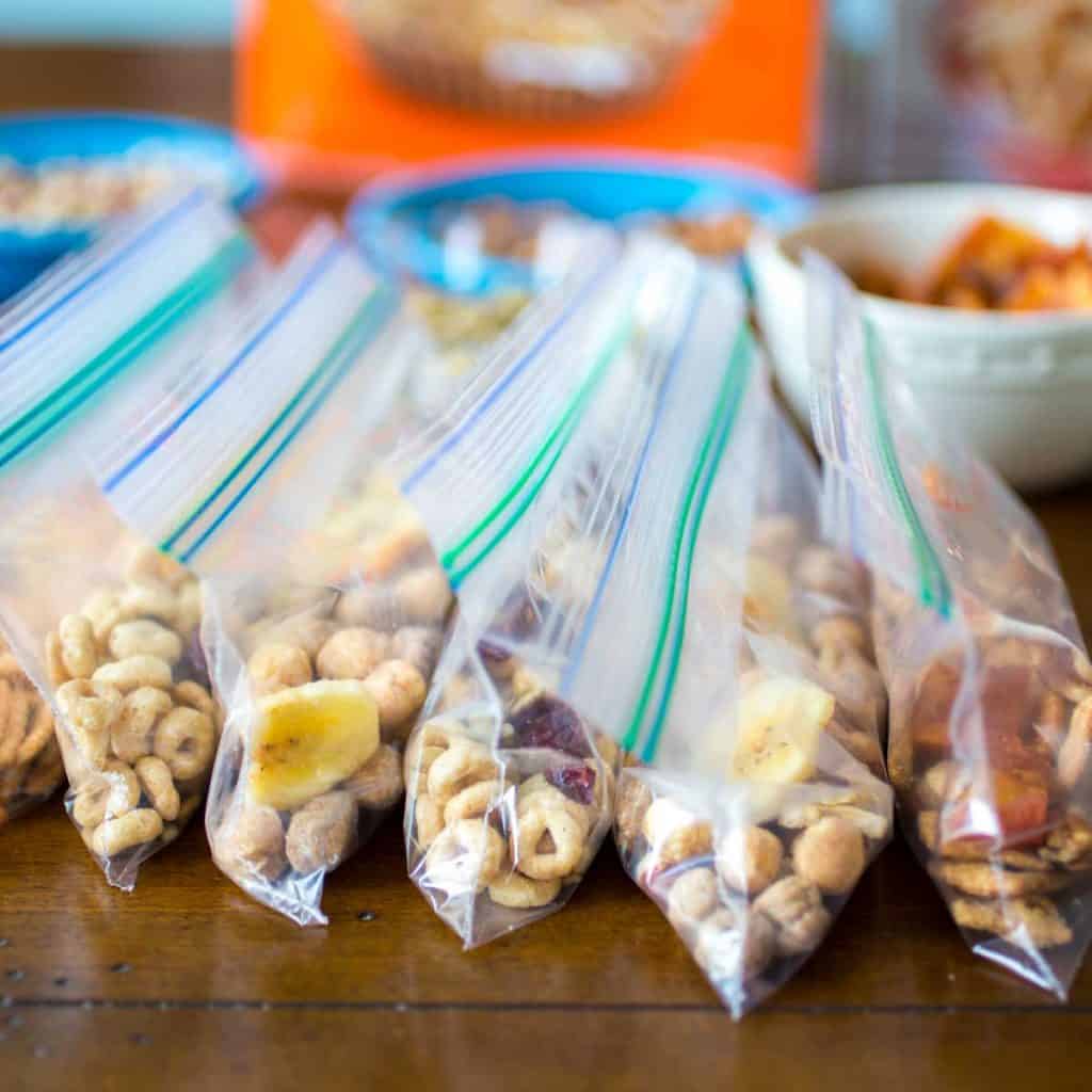 Several snack bags of homemade trail mix are lined up before a road trip.