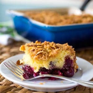 A slice of cherry almond coffee cake shows the layer of big fresh cherries on the bottom and the crumbly streusel topping on top.