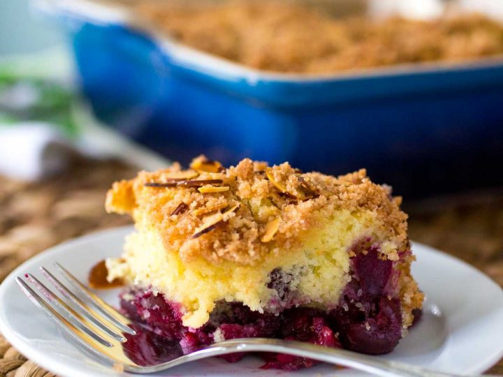 A slice of cherry almond coffee cake shows the layer of big fresh cherries on the bottom and the crumbly streusel topping on top.