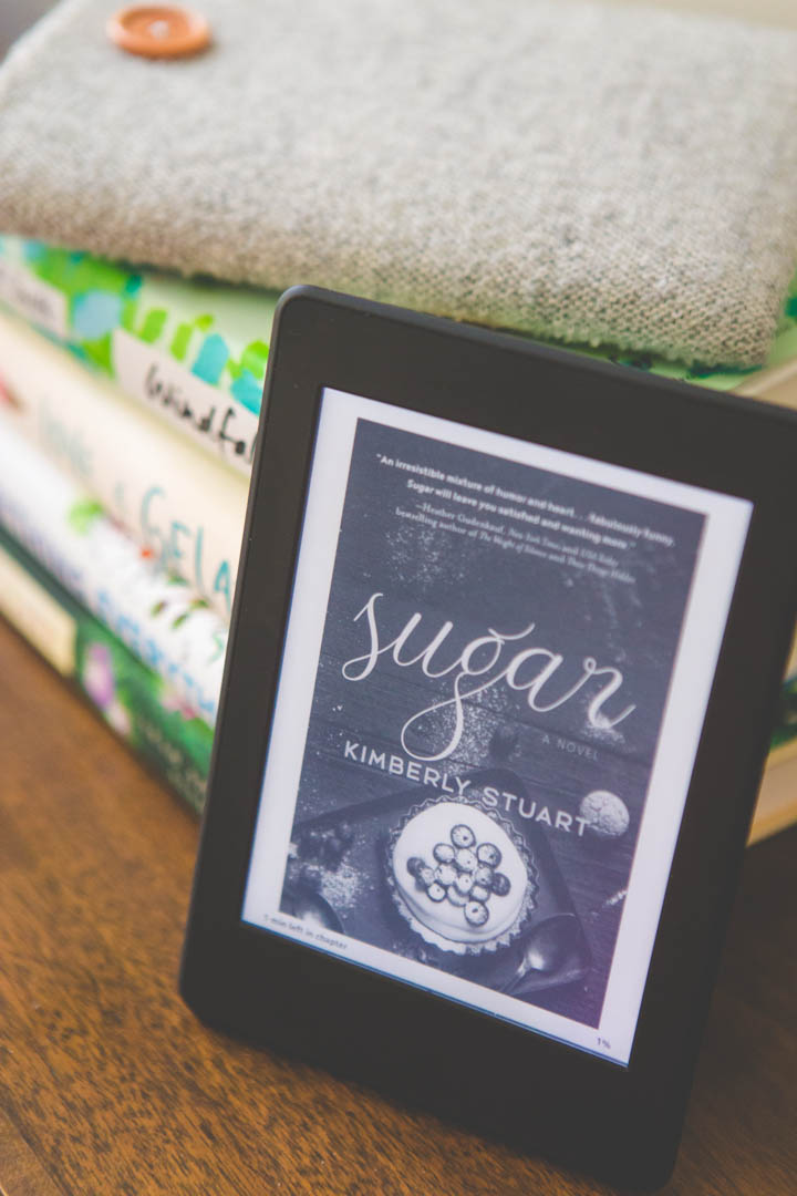 A Kindle reader has the book "Sugar" by Kimberly Stuart on the lock screen.